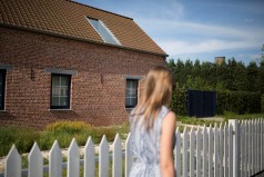 Une jeune femme devant une maison située en Flandre en Belgique